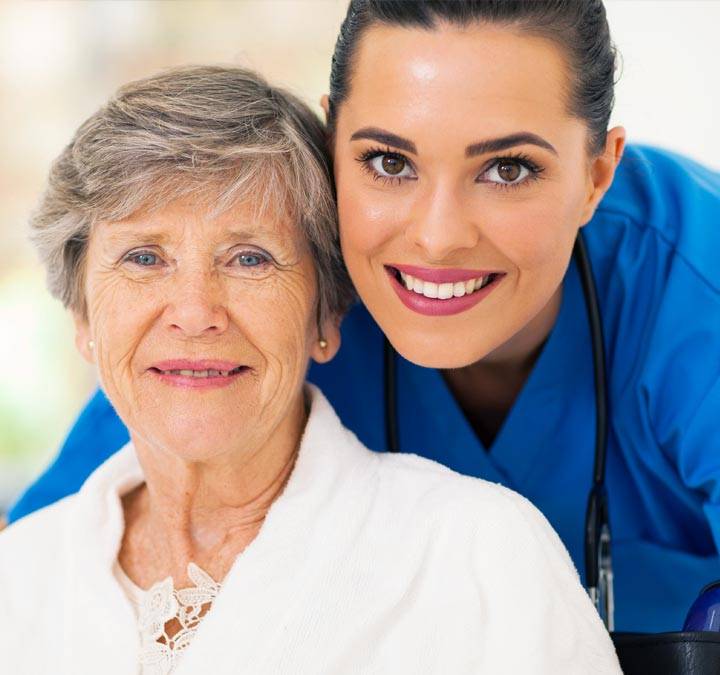 Nurse & Patient Female resident and her caregiver smiling at the camera.