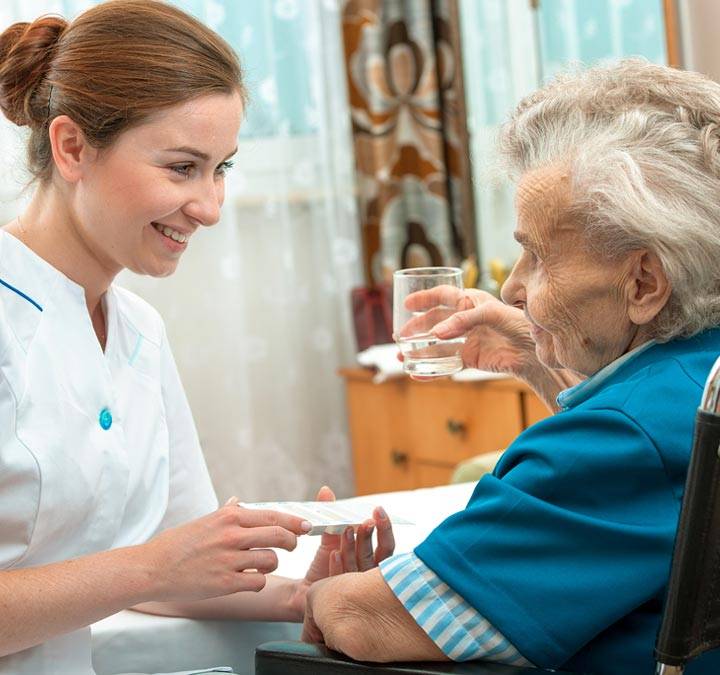 Arlington Caregiver smiling at resident while giving medication.