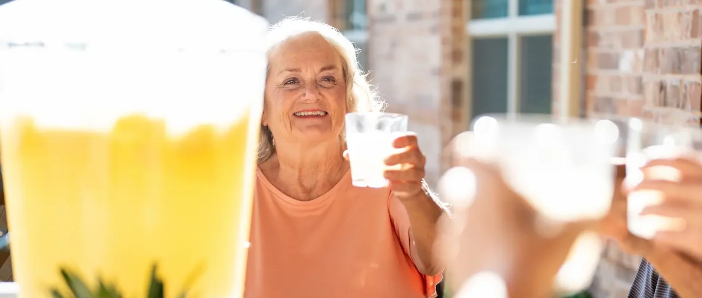 A memory care resident enjoying a glass of lemonade in the secure outdoor patio at Avalon Memory Care.