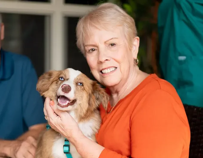 A memory care resident enjoying pet therapy with a brown and white therapy dog.