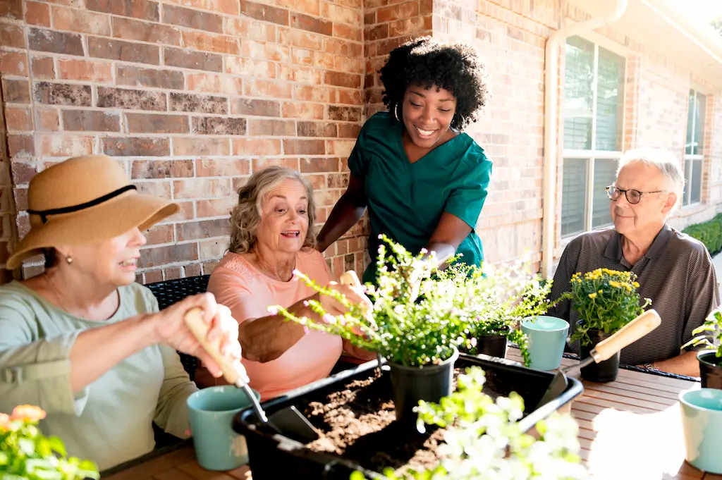 Two memory care residents and a staff member enjoying a gardening activity designed to enhance quality of life.