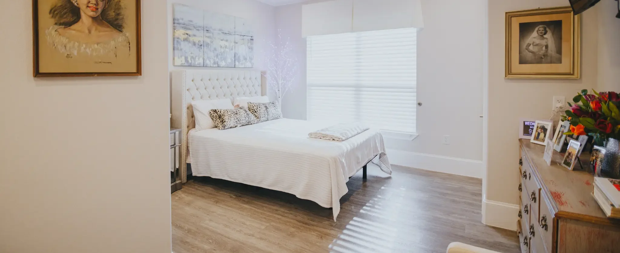 A spacious bedroom at Avalon Memory Care with white furnishings and personalized decor.