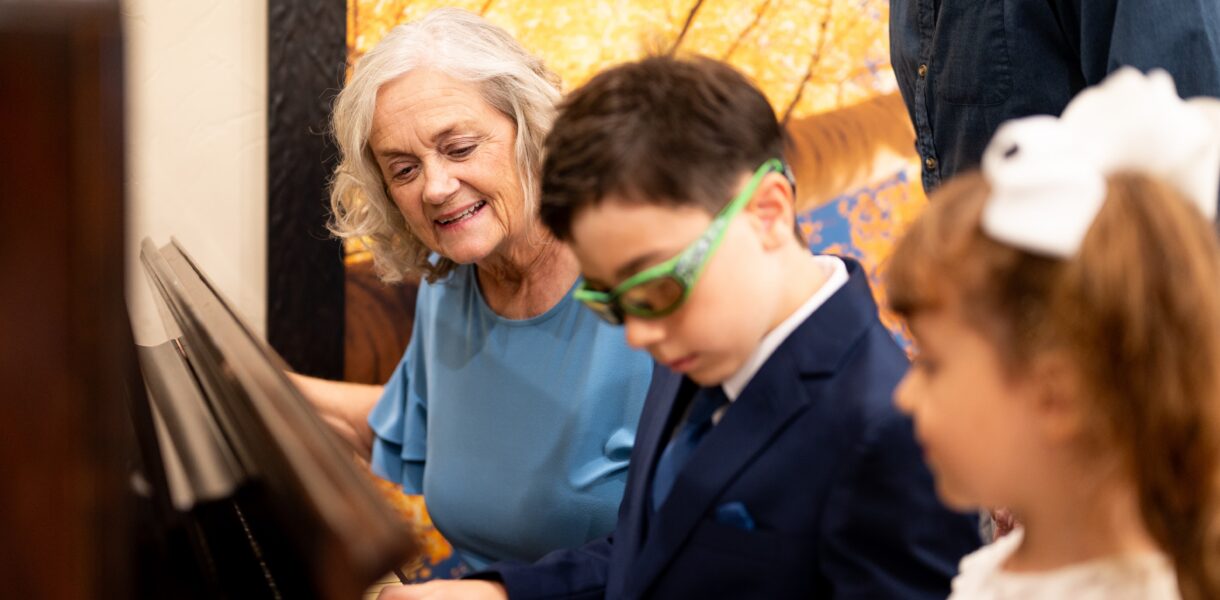 A senior teaching children to play piano
