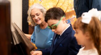 A senior teaching children to play piano